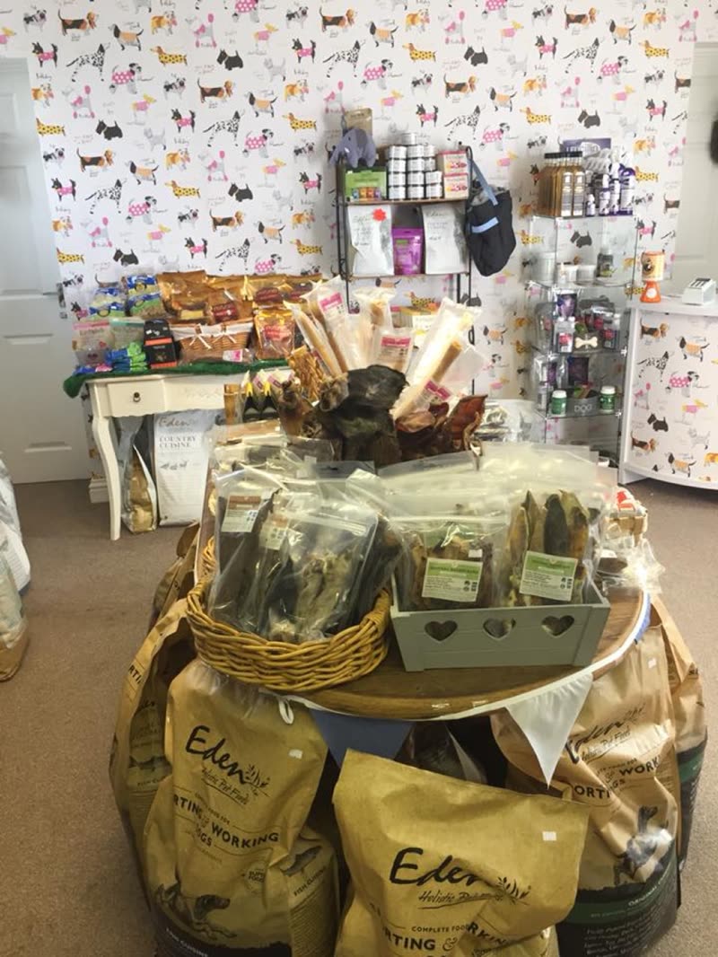 Inside the shop: dog-print wallpaper, a wicker basket of natural chews and sacks of dry food on the floor